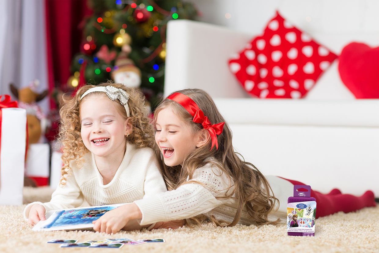 dwie dziewczynki leżące na dywanie i grające w karty